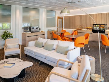 a room with white couches and orange chairs