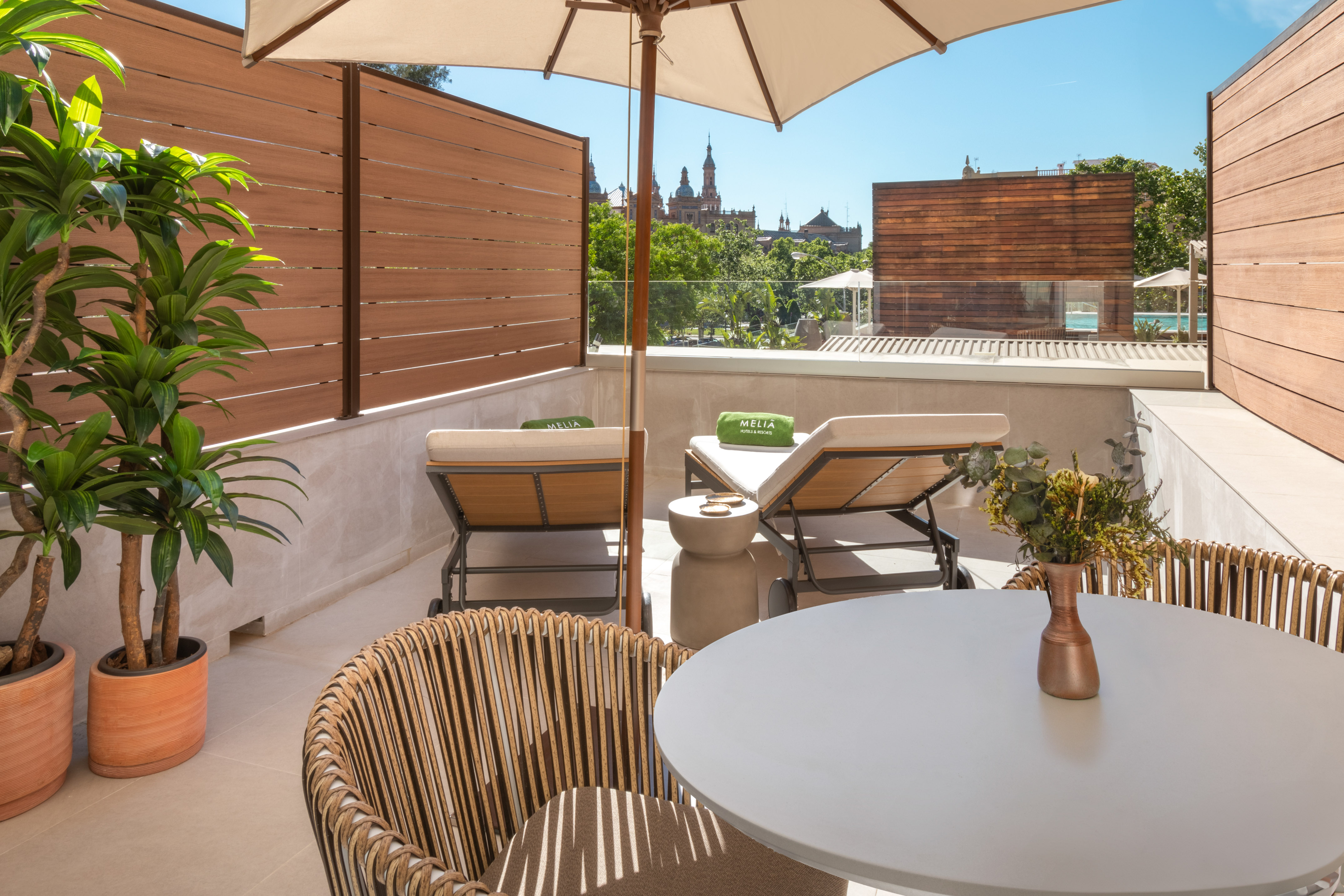 Meliá hotel terrace with sun loungers, umbrella, and Seville city view.