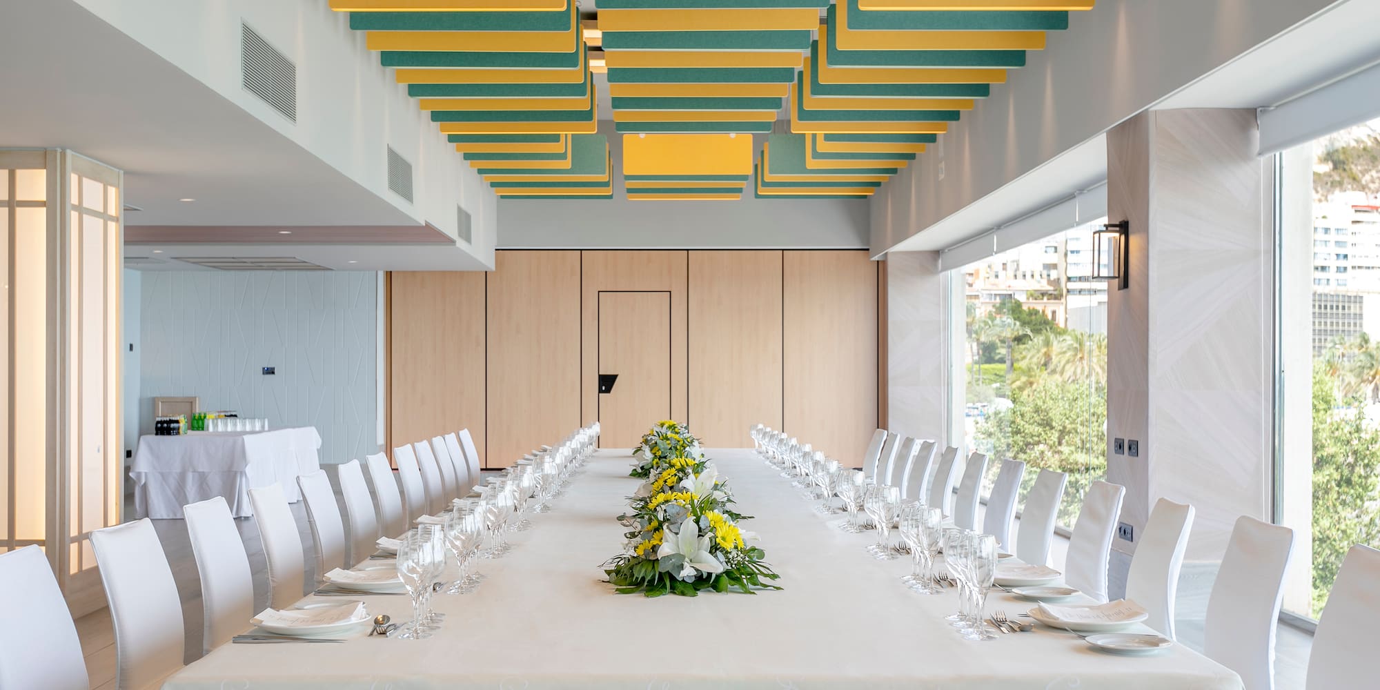 a long table with white chairs and yellow flowers