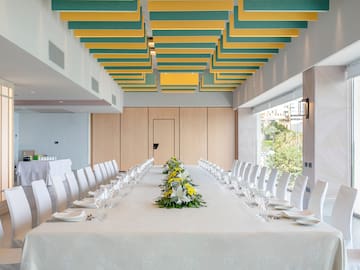 a long table with white chairs and yellow flowers