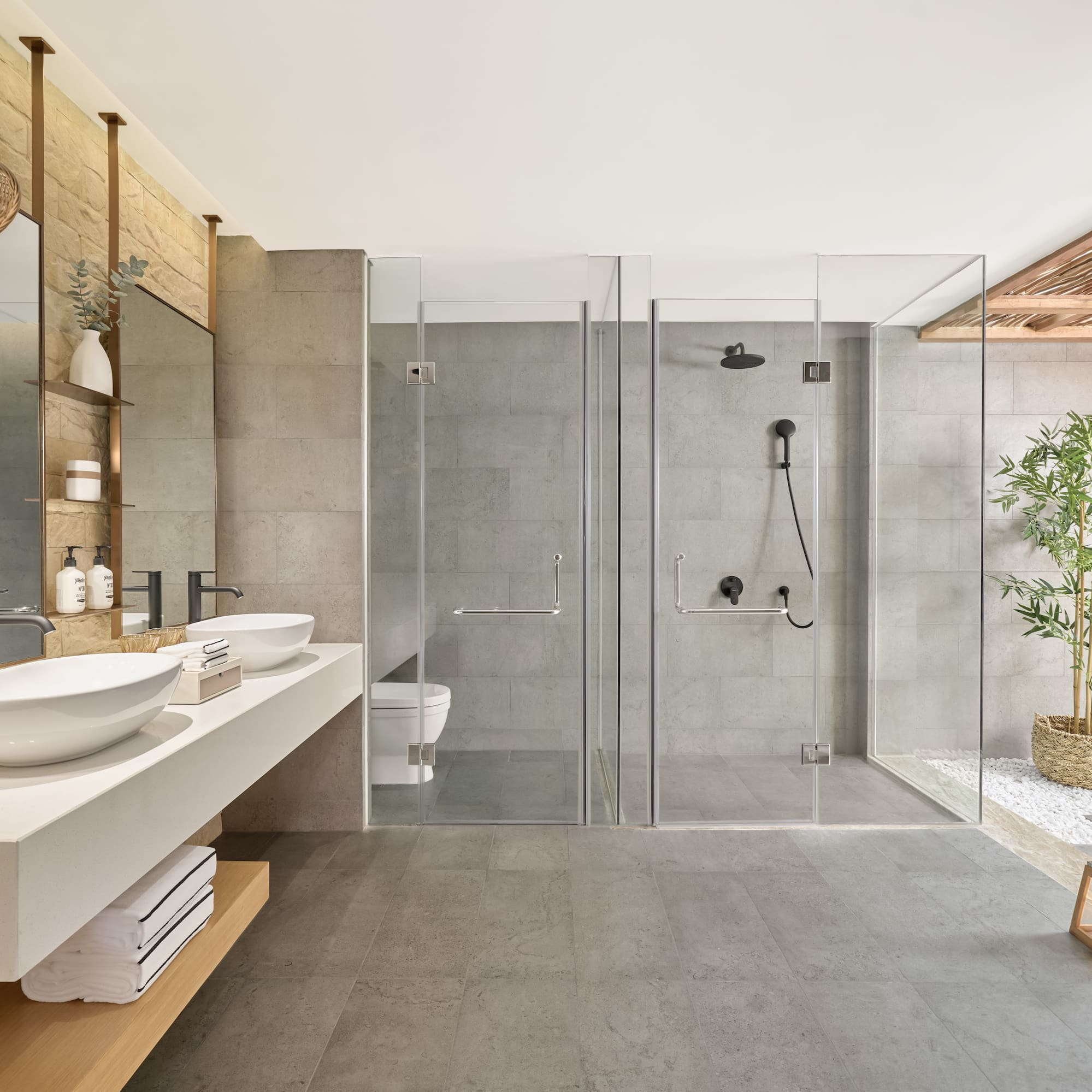 Modern bathroom with dual vanity, glass showers, and spa-like decor.