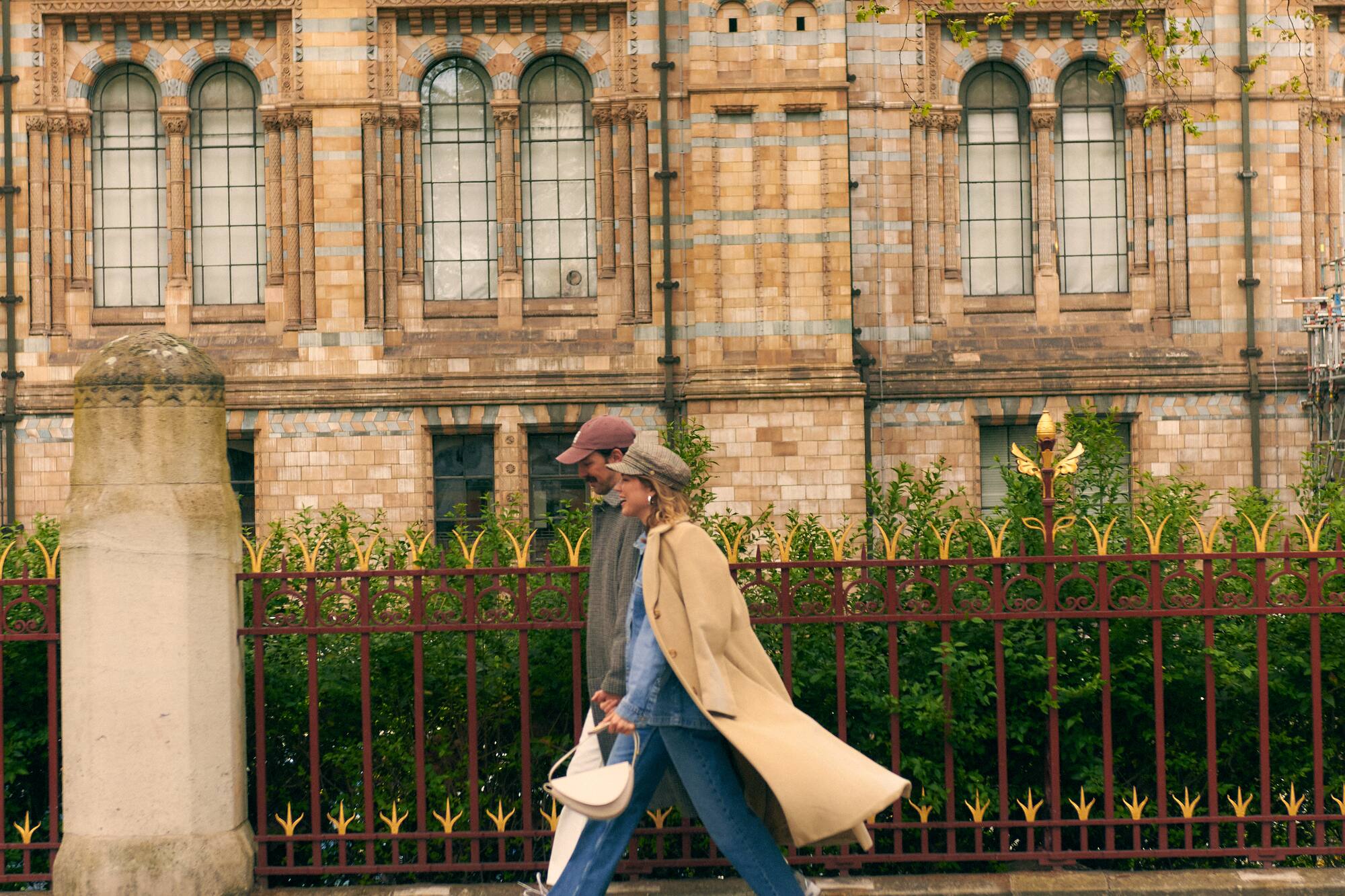 Pareja caminando en Londres frente al Museo de Historia Natural.