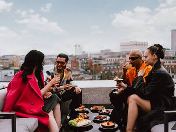 a group of people sitting on a rooftop eating food