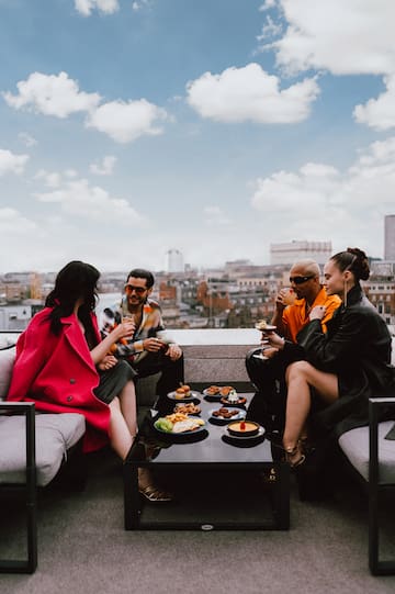 a group of people sitting on a rooftop eating food