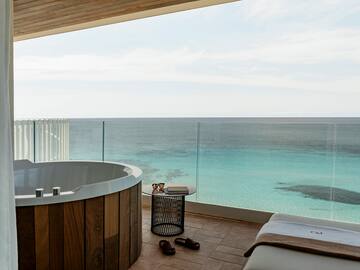 a room with a hot tub and a view of the ocean