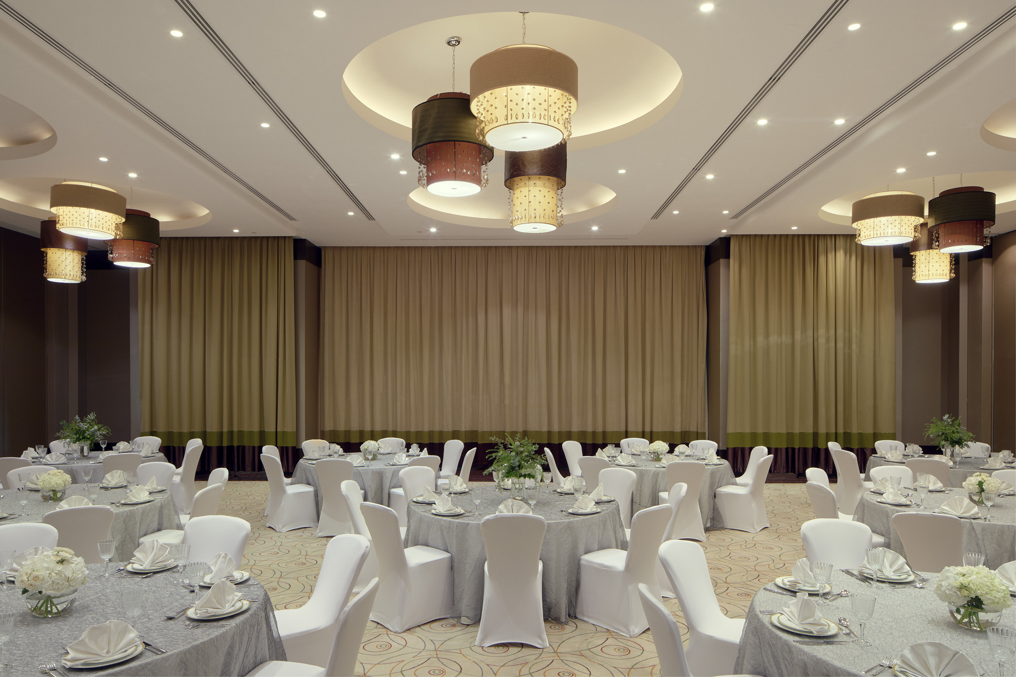 Elegant ballroom with set banquet tables, white chairs, and stylish chandeliers.
