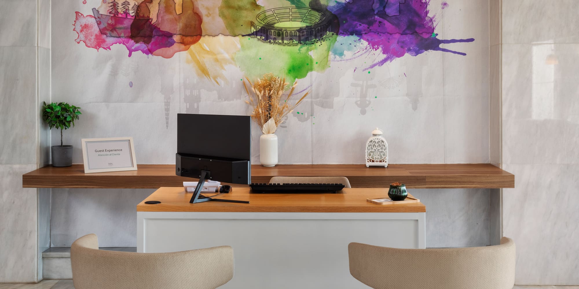 a desk with a computer and a painting on the wall