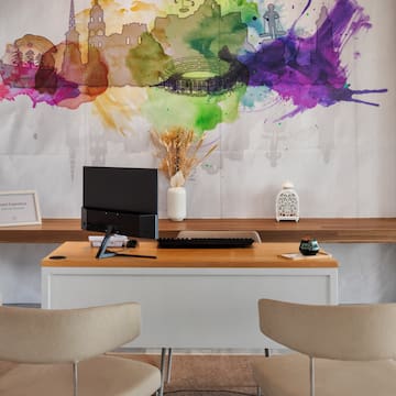 a desk with a computer and a painting on the wall