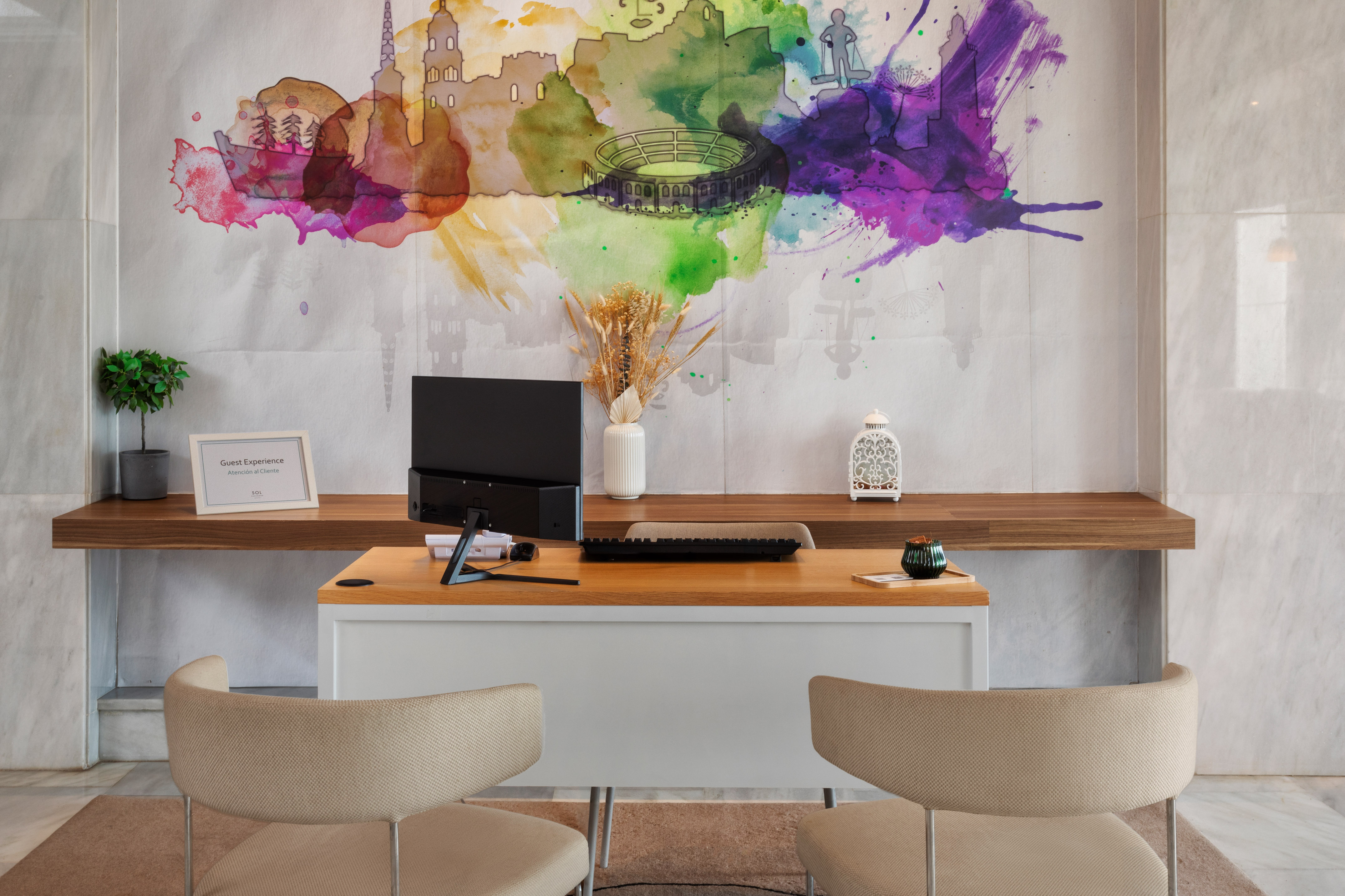 a desk with a computer and a painting on the wall