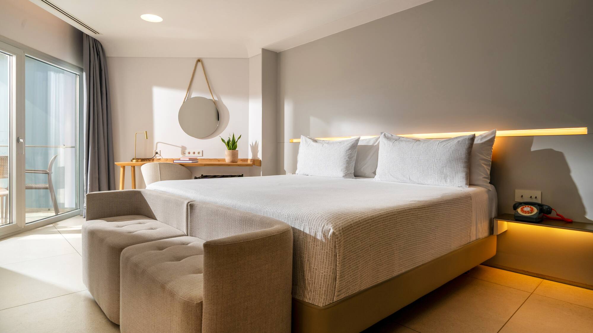 a bed with a couch and a mirror in a room