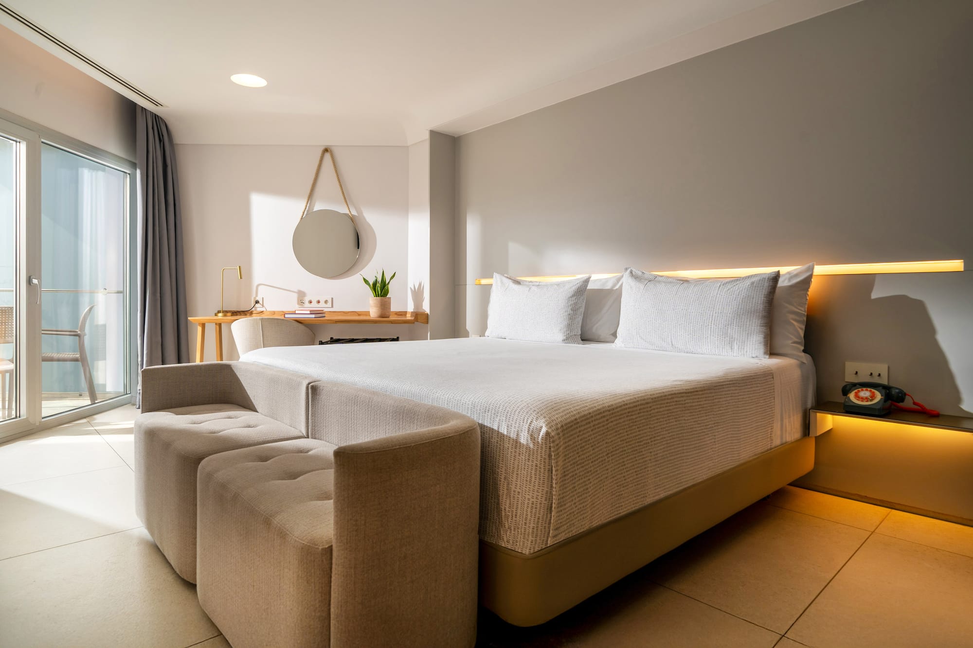 a bed with a couch and a mirror in a room