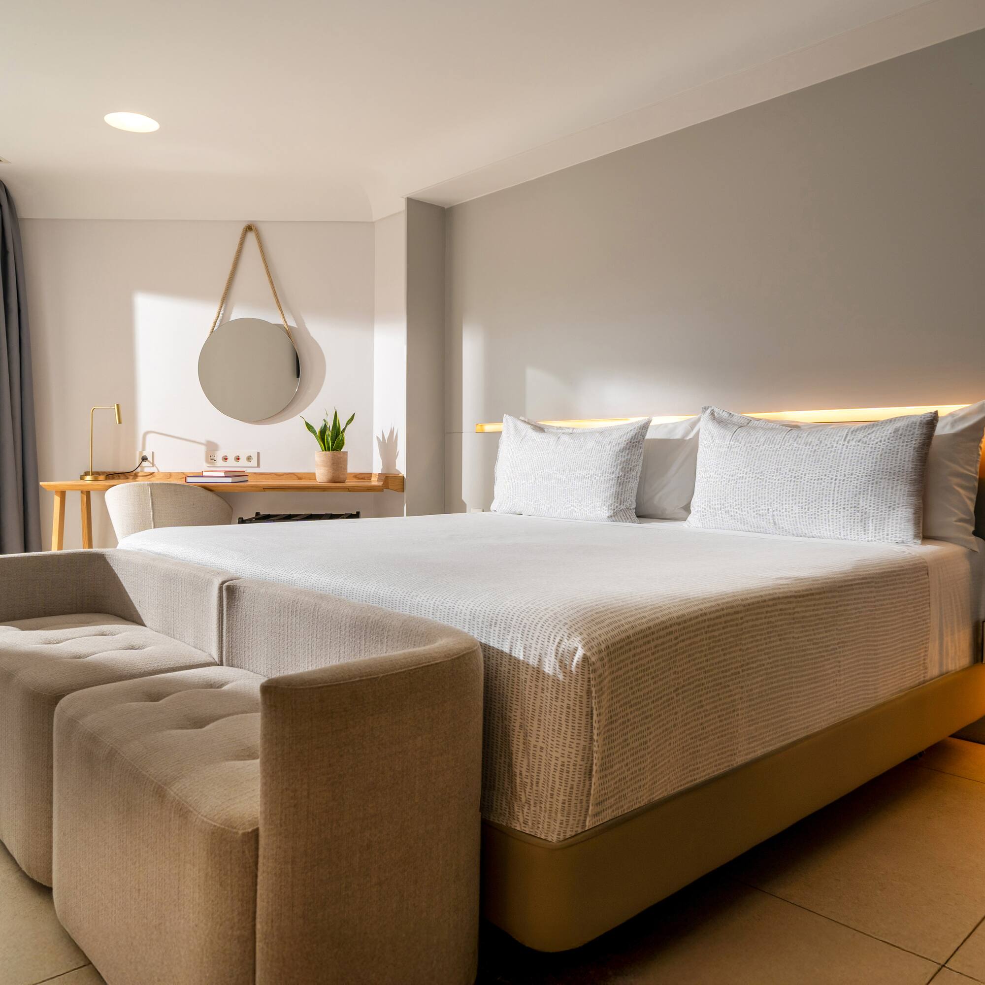 a bed with a couch and a mirror in a room