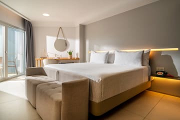 a bed with a couch and a mirror in a room