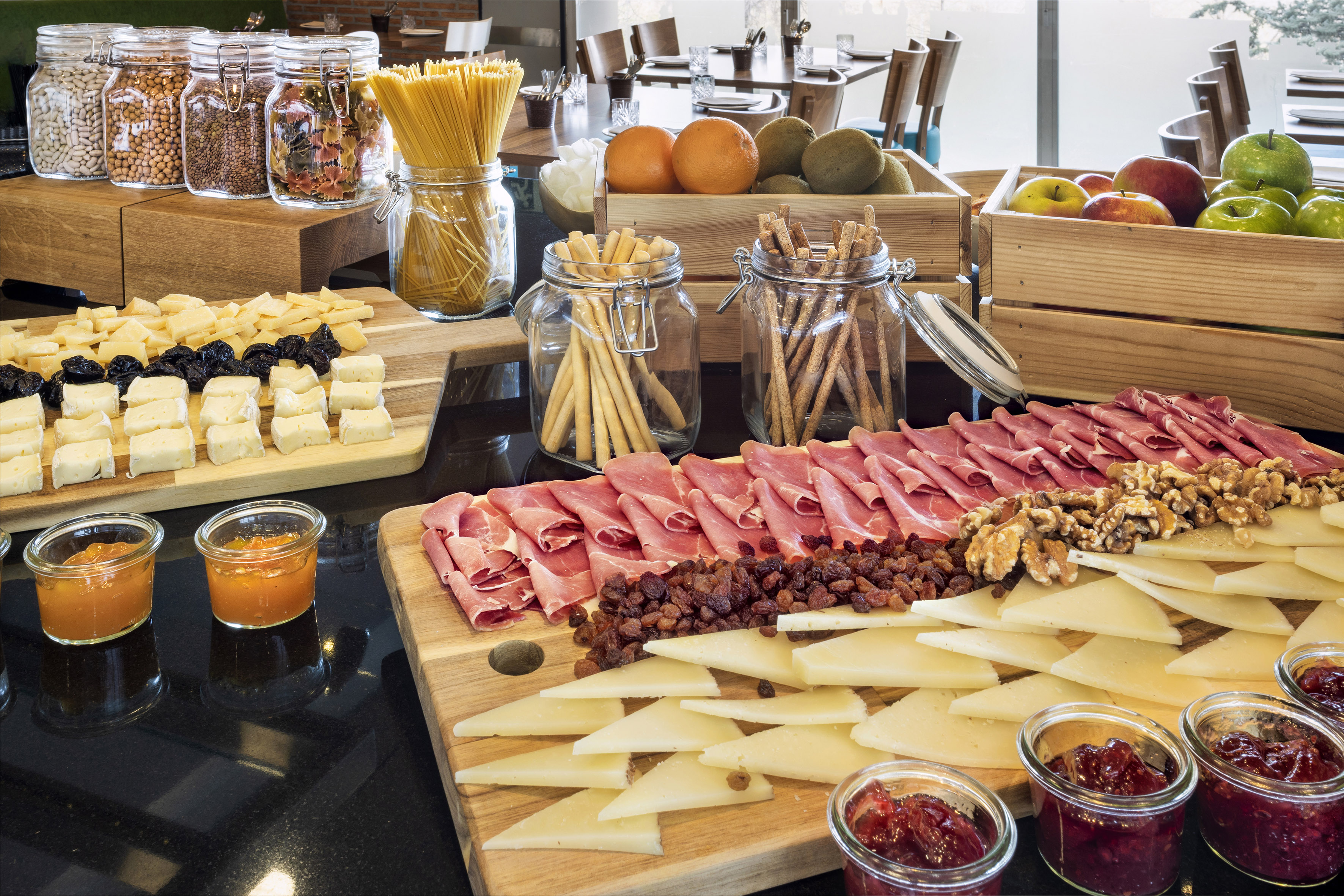 Buffet with sliced ham, assorted cheeses, prunes, walnuts, breadsticks, and fresh fruit.