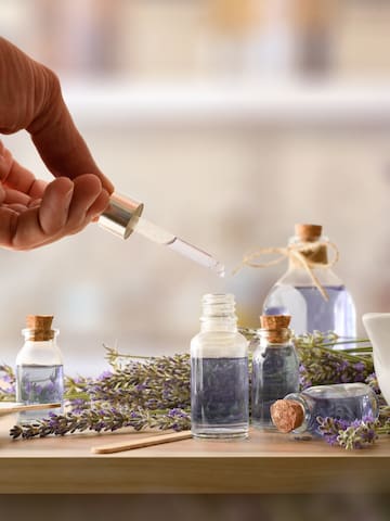 a hand holding a dropper over a bottle of lavender