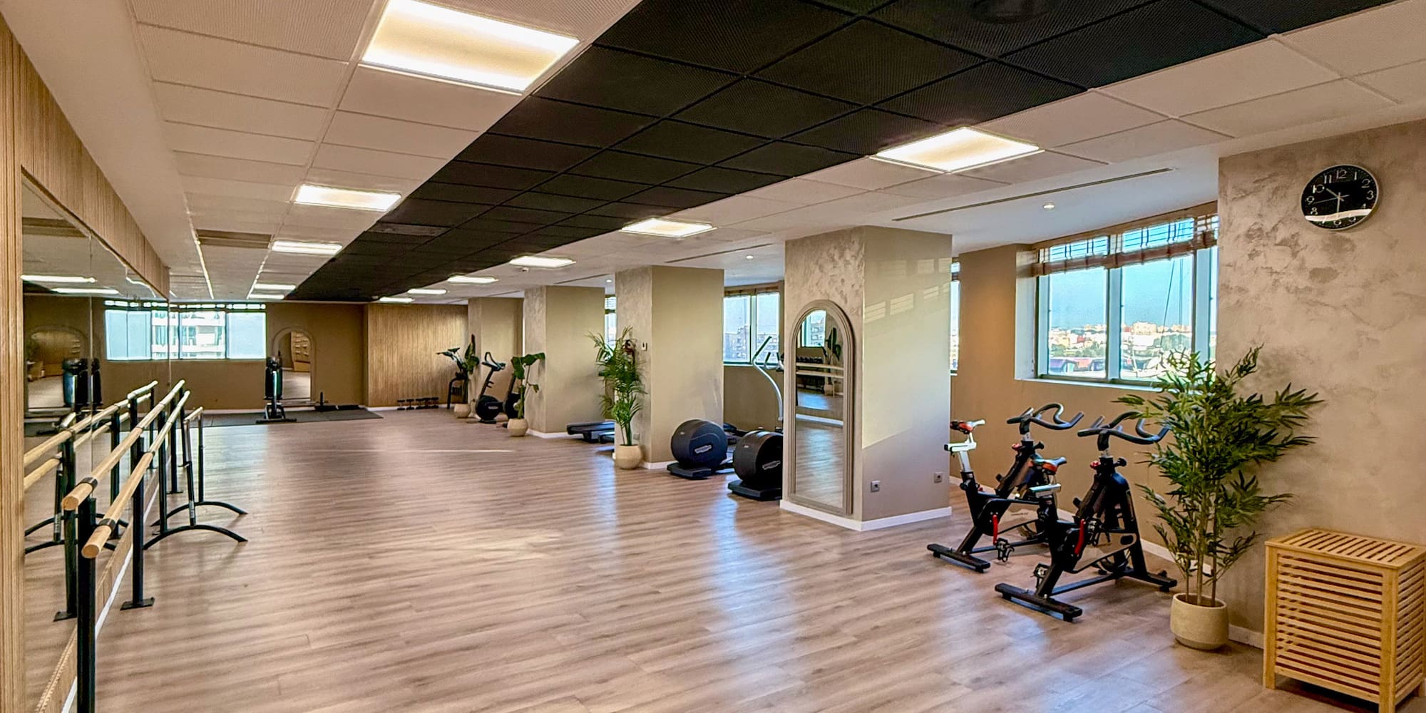 Modern fitness studio with ballet barres, spin bikes, and wood flooring.