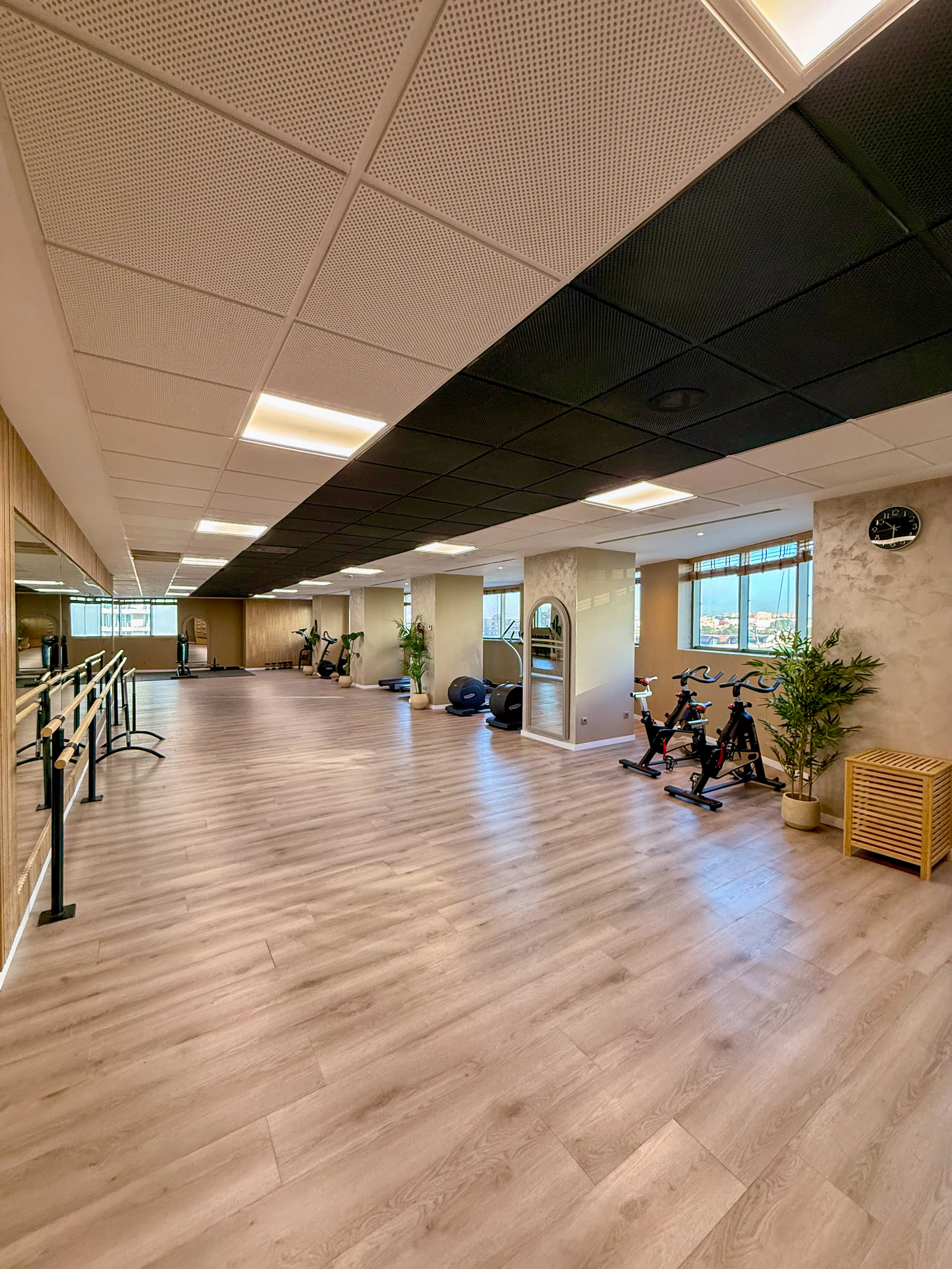 Modern fitness studio with ballet barres, spin bikes, and wood flooring.