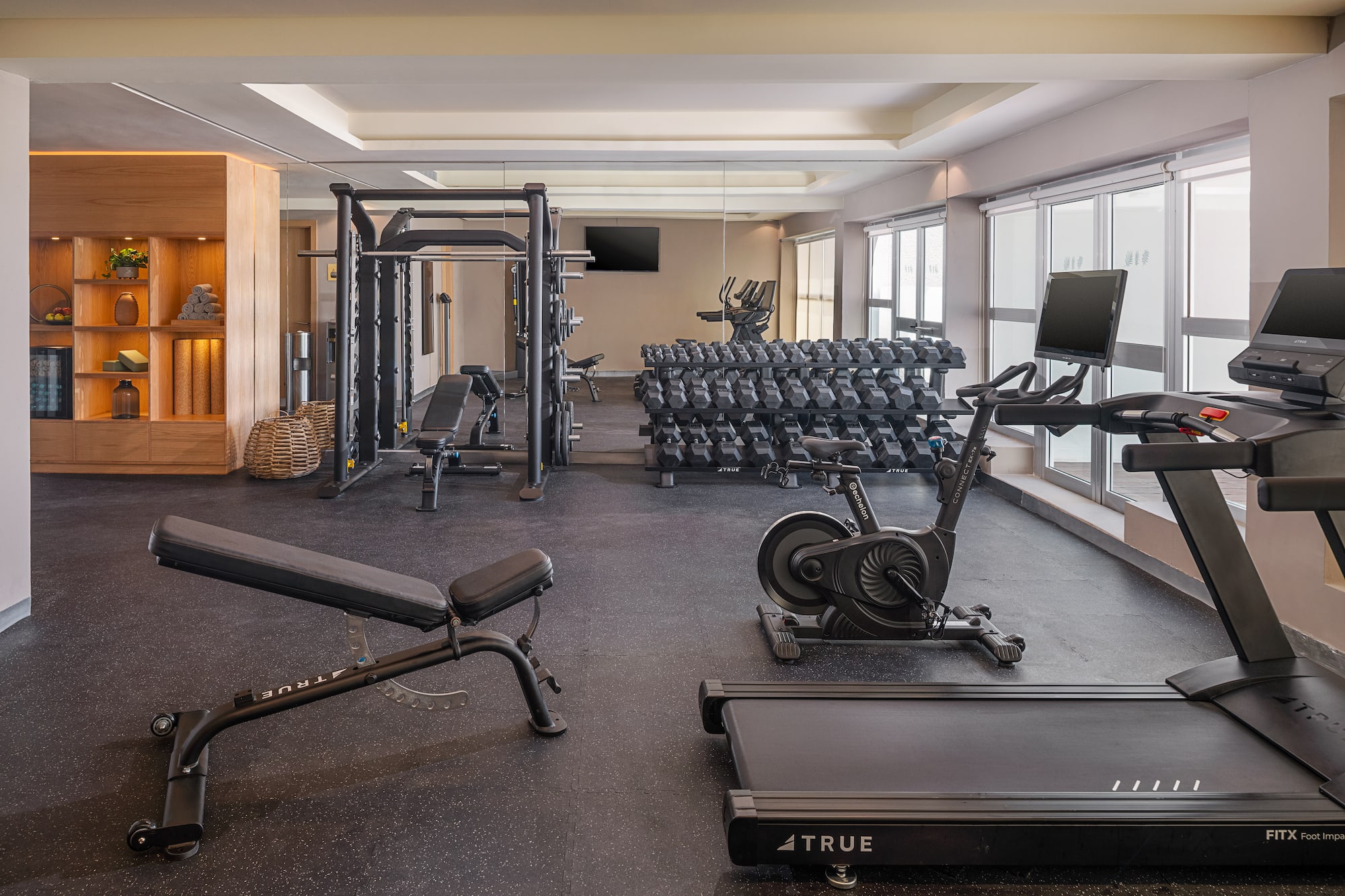 Hotel fitness center with treadmill, spin bike, dumbbells, weight bench.
