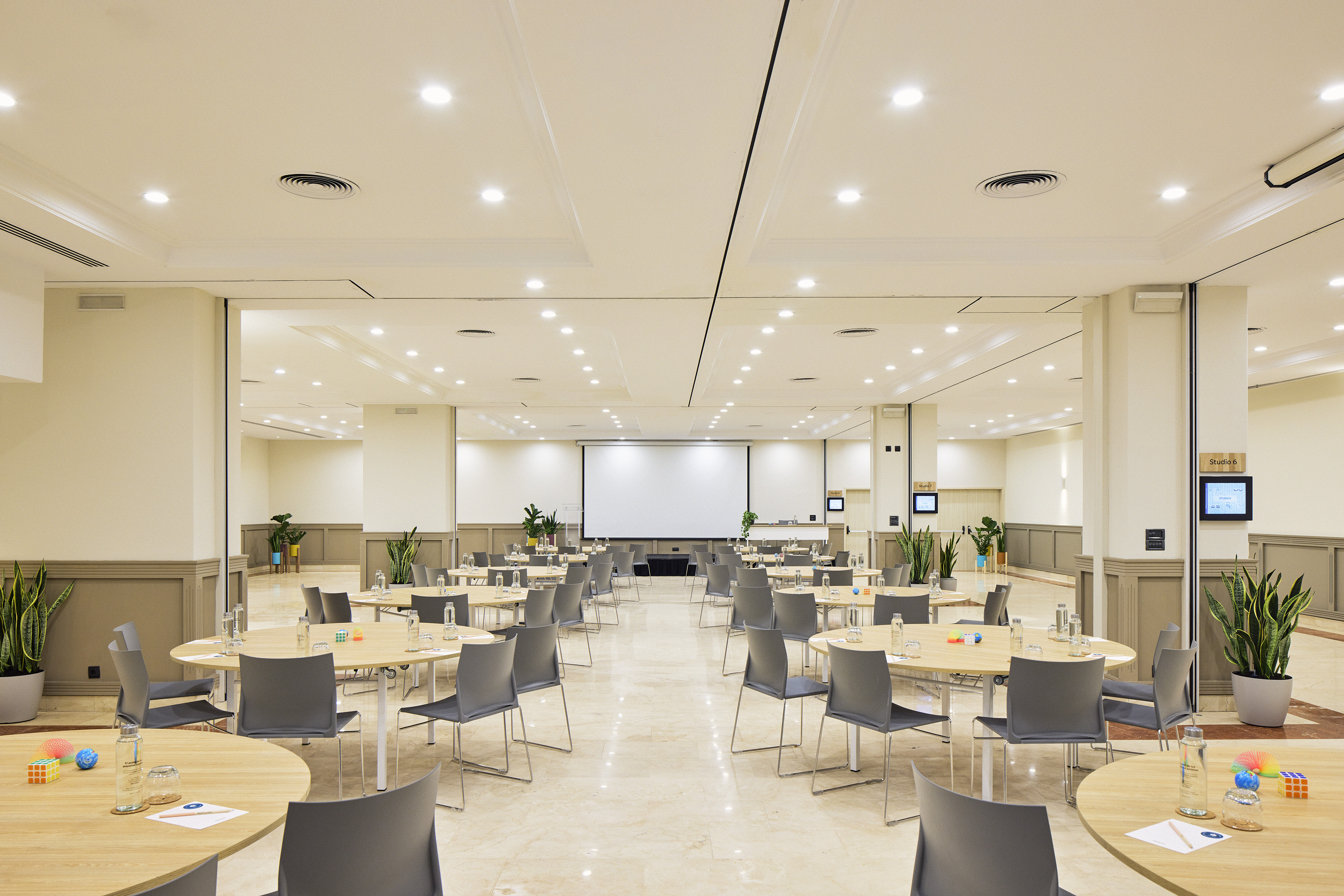 Bright conference room with round tables, chairs, and projection screen.