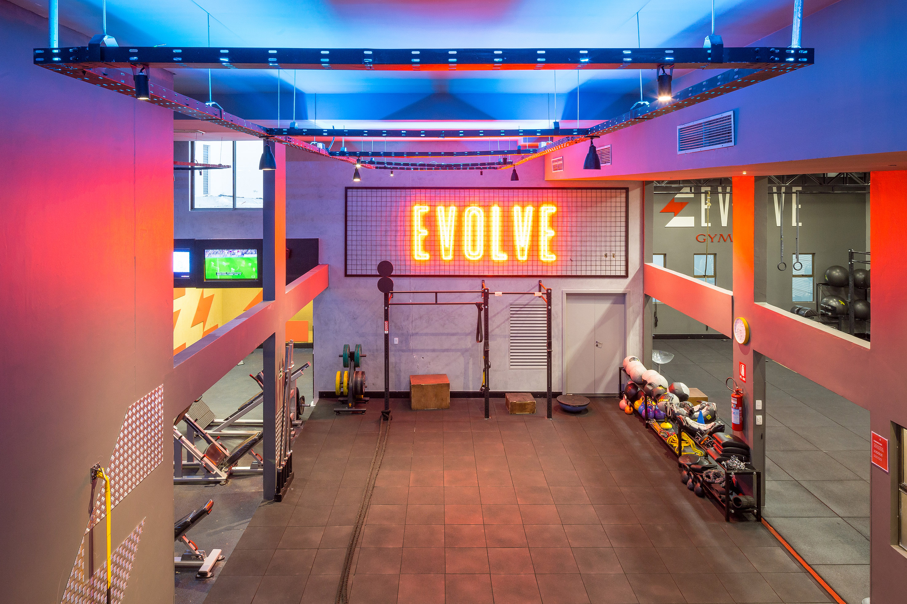 Vibrant Evolve gym interior with neon sign, fitness equipment, and dynamic lighting.