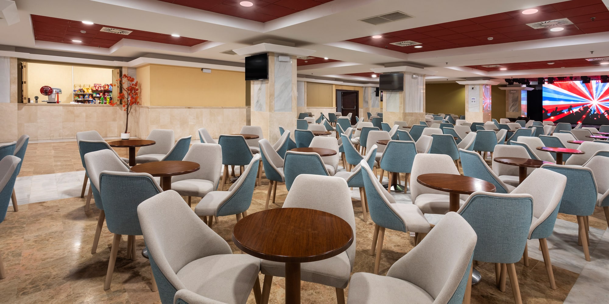 Modern hotel lounge with blue and beige upholstered chairs and round tables.