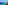 Turquoise sea coastline with sandy beach, green vegetation, and blue sky.
