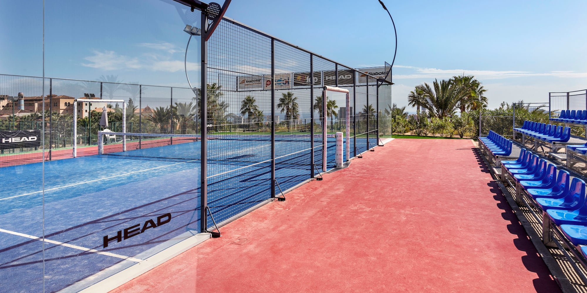 a tennis court with a fence and chairs