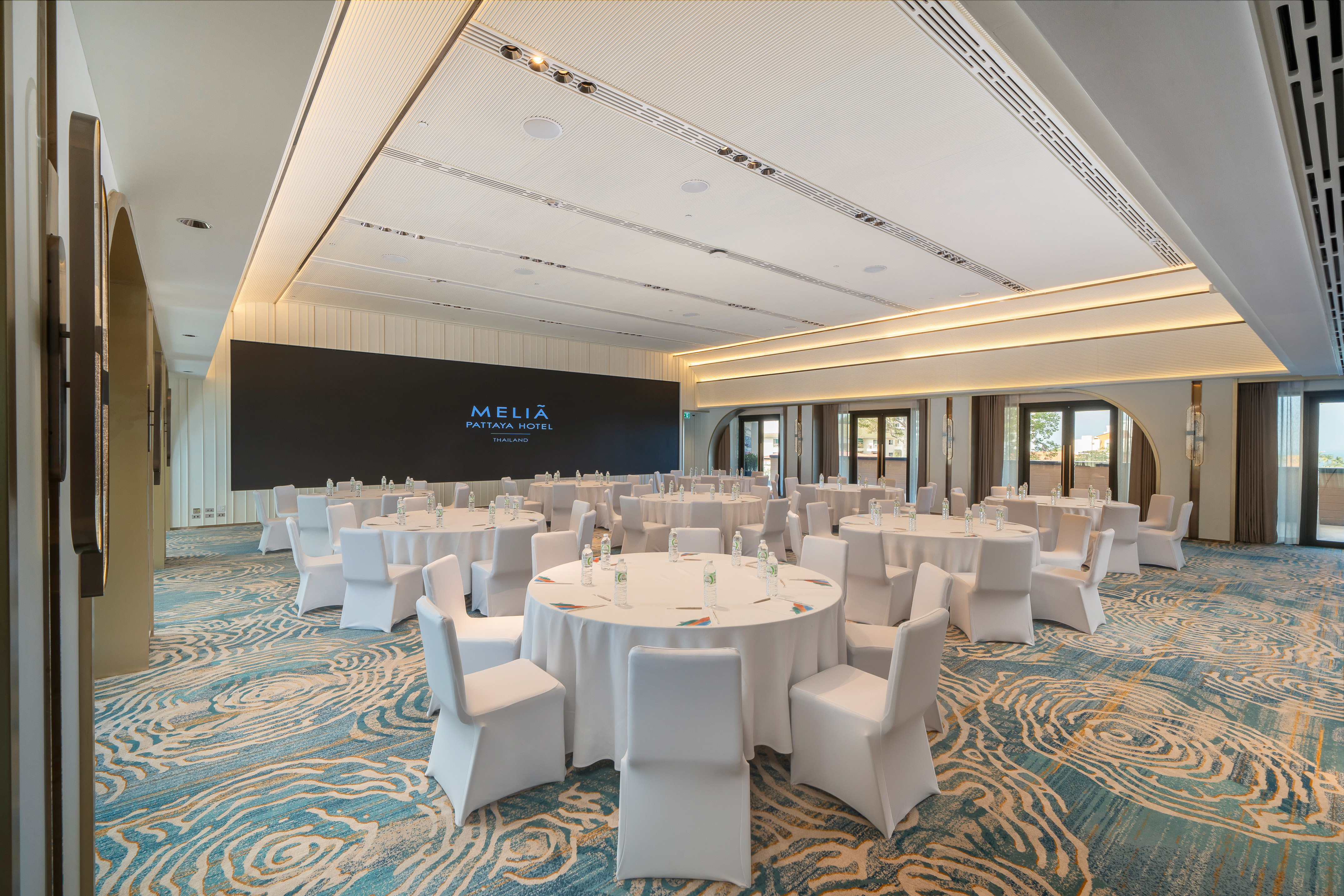 Spacious Melia Pattaya event ballroom with round tables and branding screen. - Khram - Meliá Pattaya Hotel, Pattaya