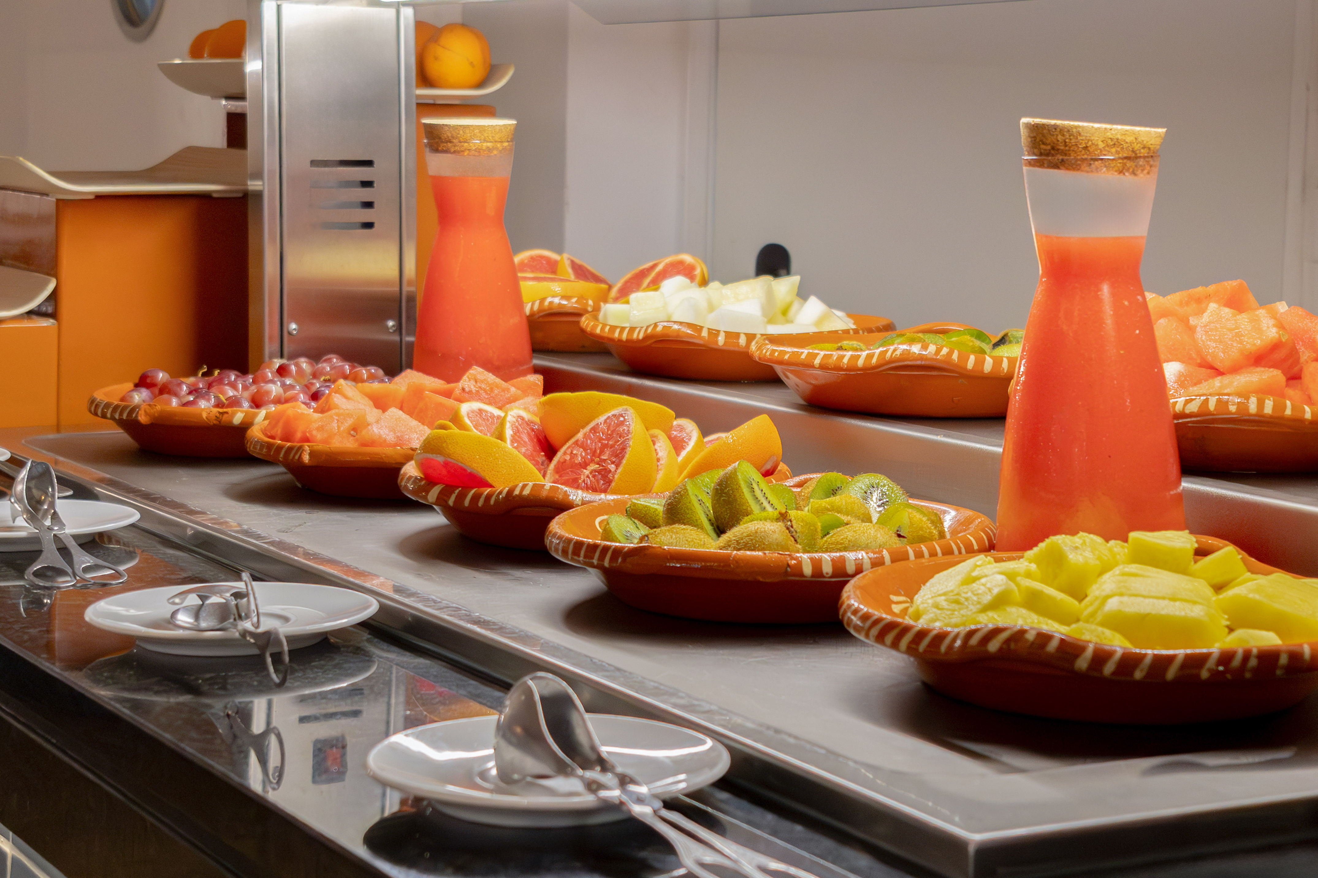 a counter with bowls of fruit and juice