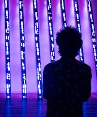 a person standing in front of a purple lit up wall