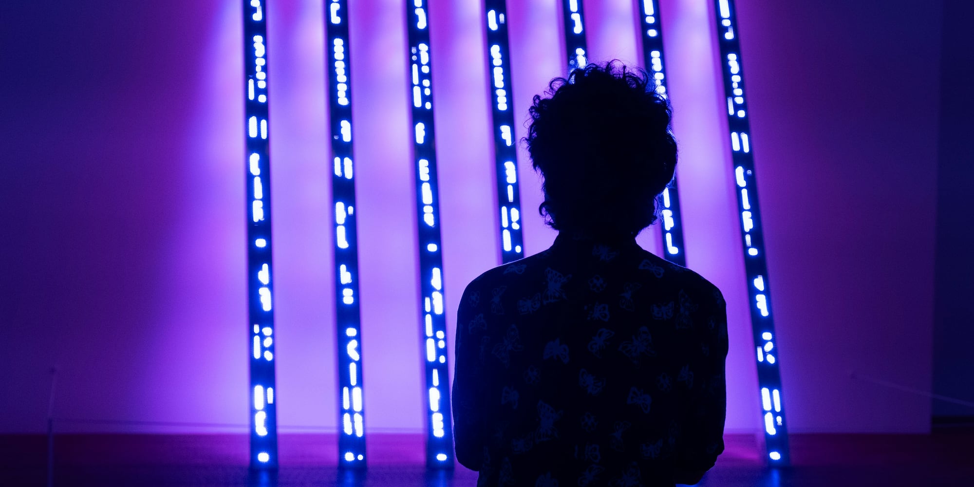 a person standing in front of a purple lit up wall