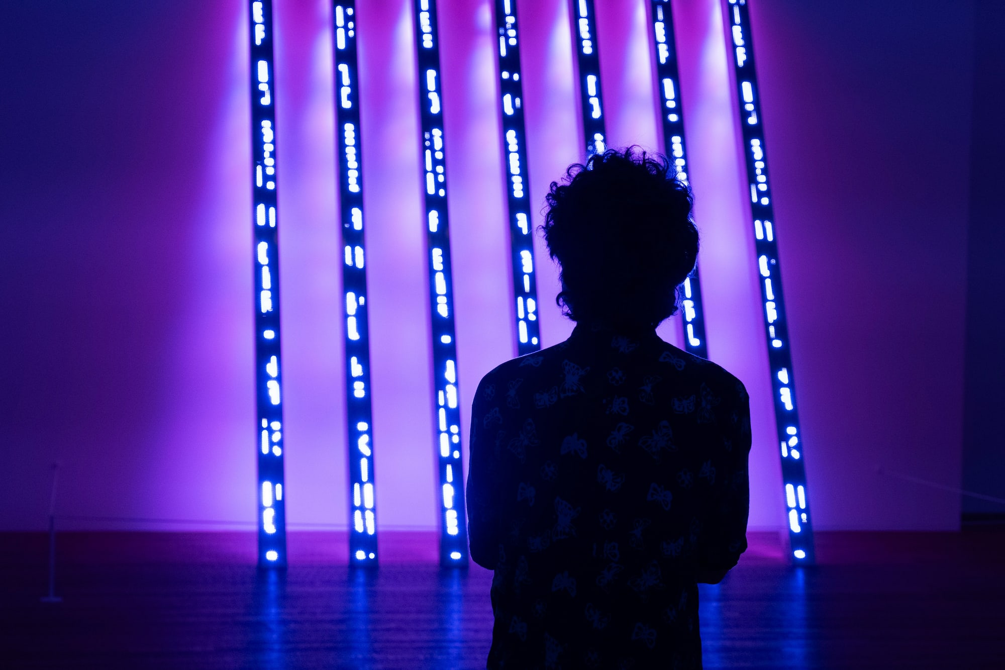 a person standing in front of a purple lit up wall