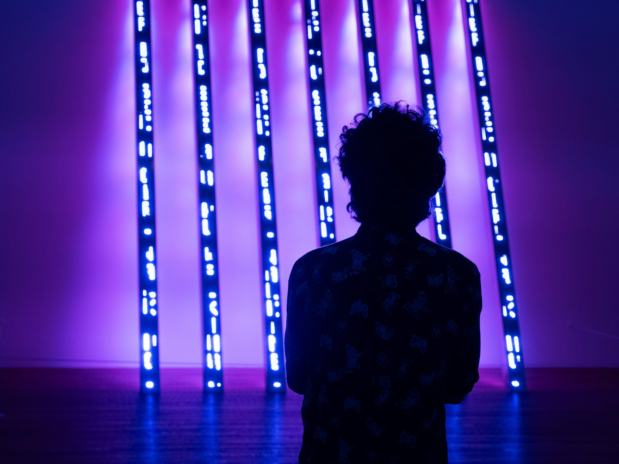 a person standing in front of a purple lit up wall