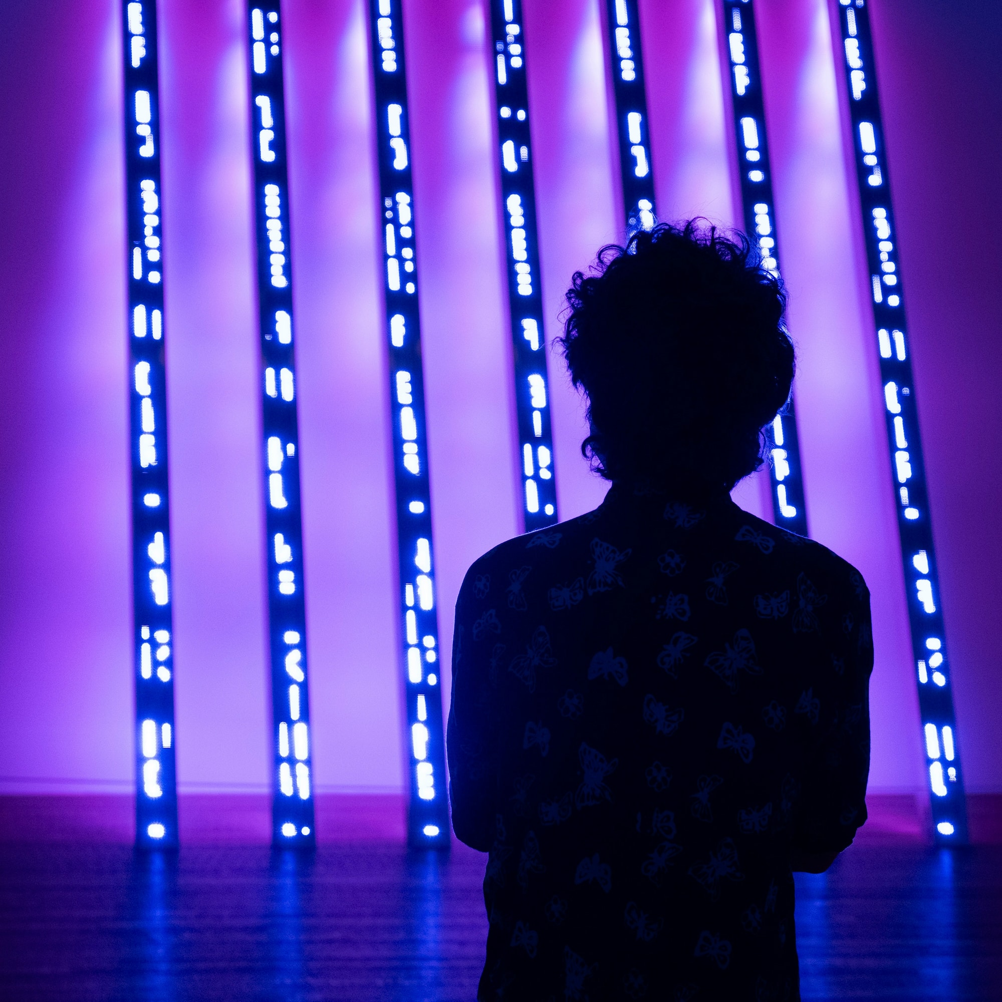 a person standing in front of a purple lit up wall