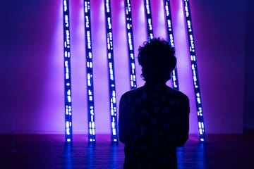 a person standing in front of a purple lit up wall
