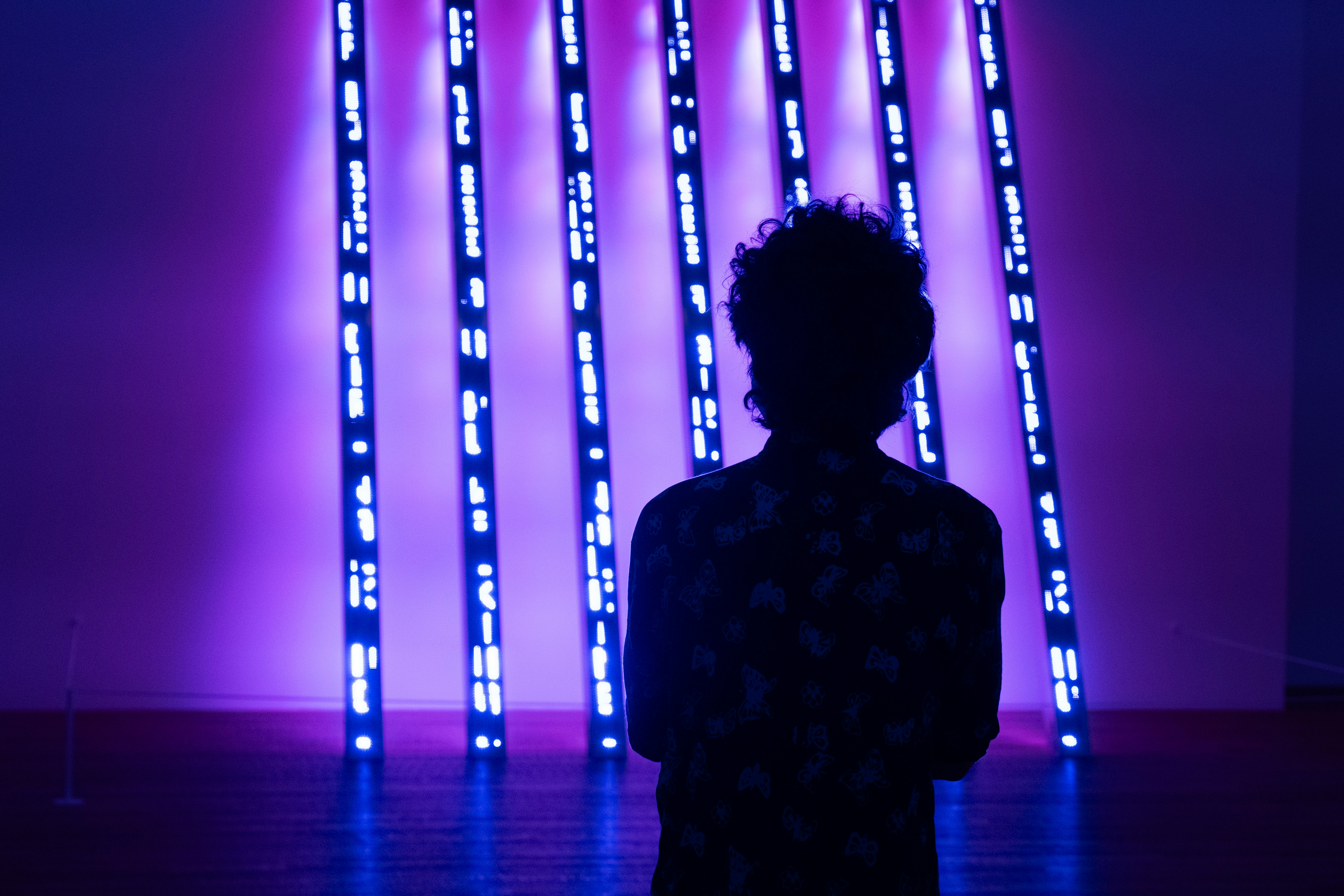 a person standing in front of a purple lit up wall