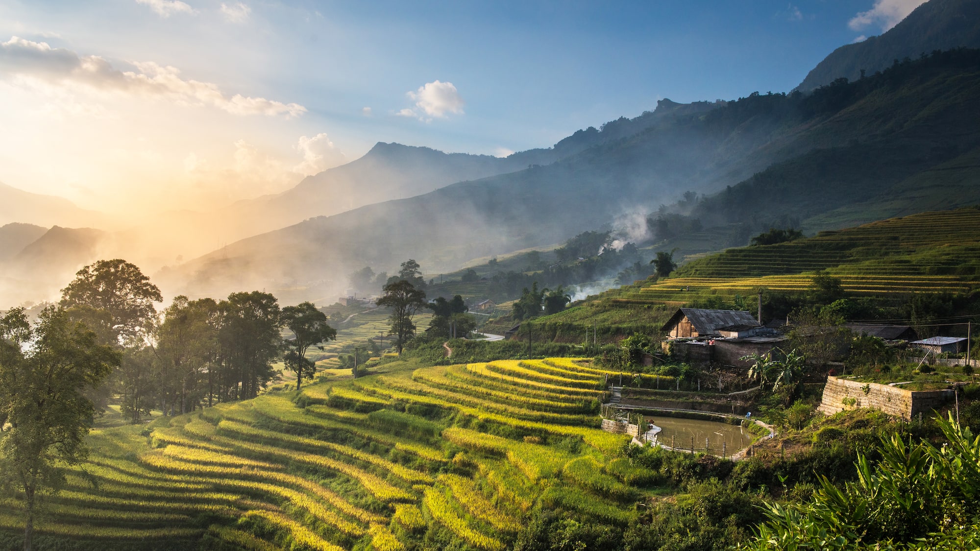 a house on a hillside with trees and mountains in the background