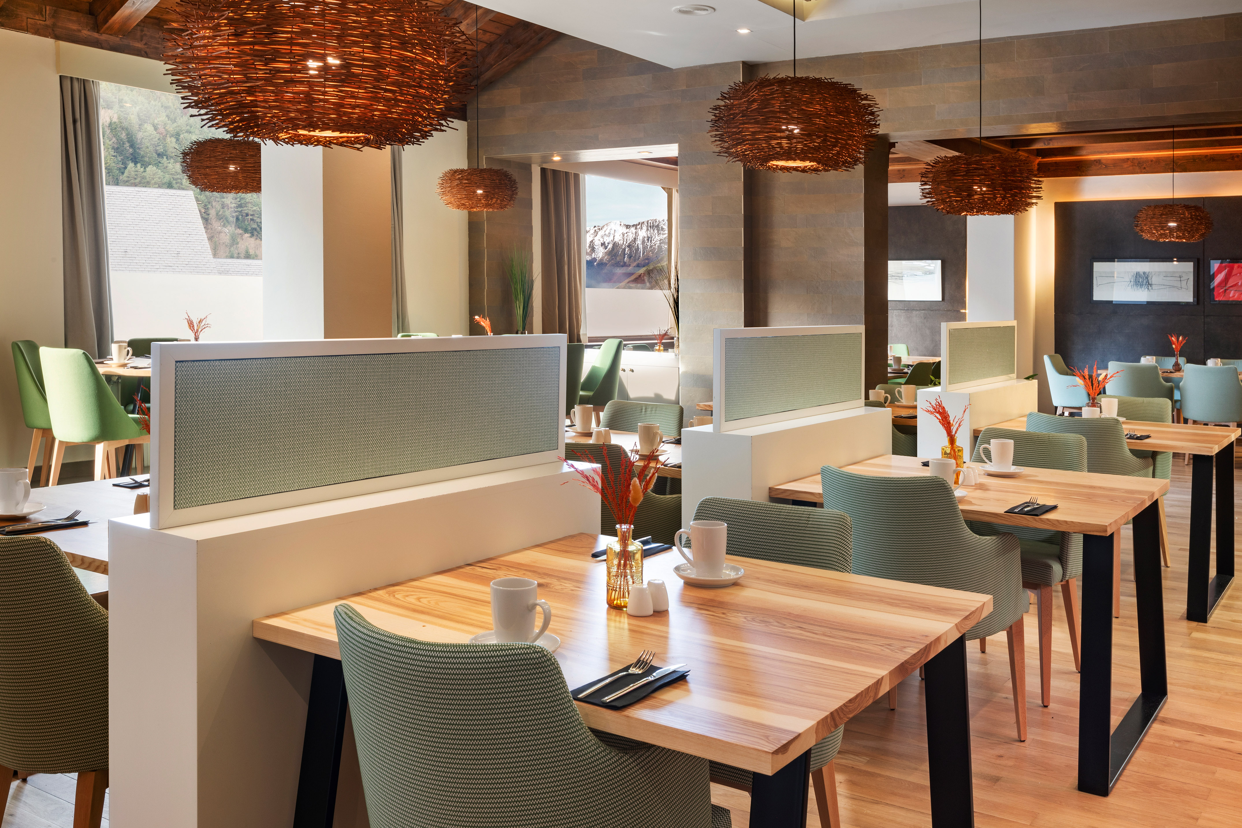 Modern restaurant with wooden tables, green chairs, woven lights, mountain view.