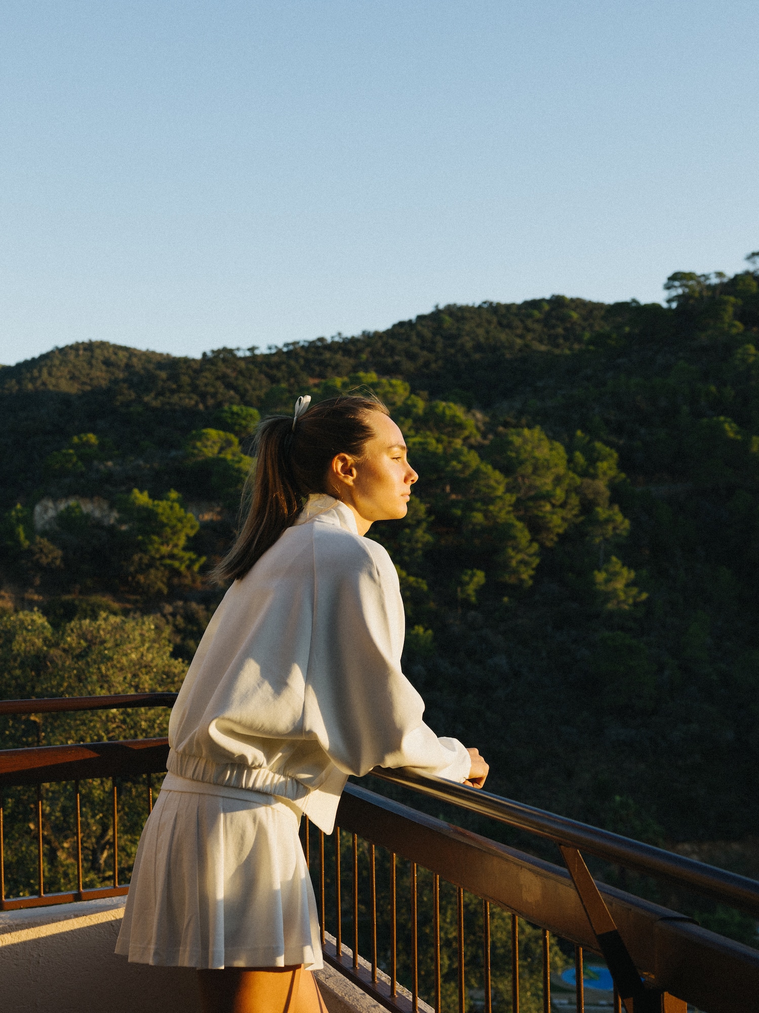 a woman standing on a balcony overlooking a forest