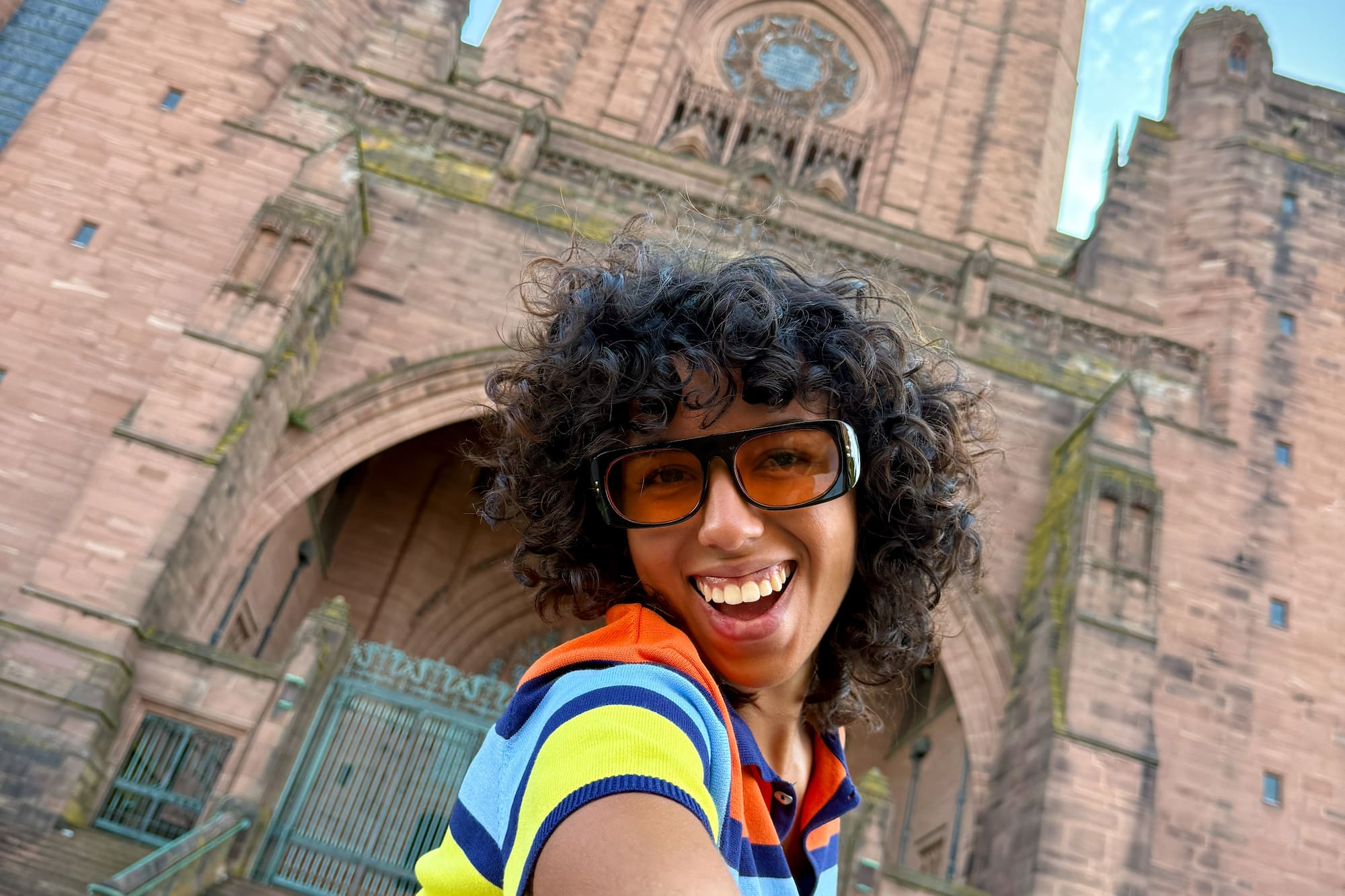 Smiling woman in orange sunglasses taking a selfie at Liverpool Cathedral.