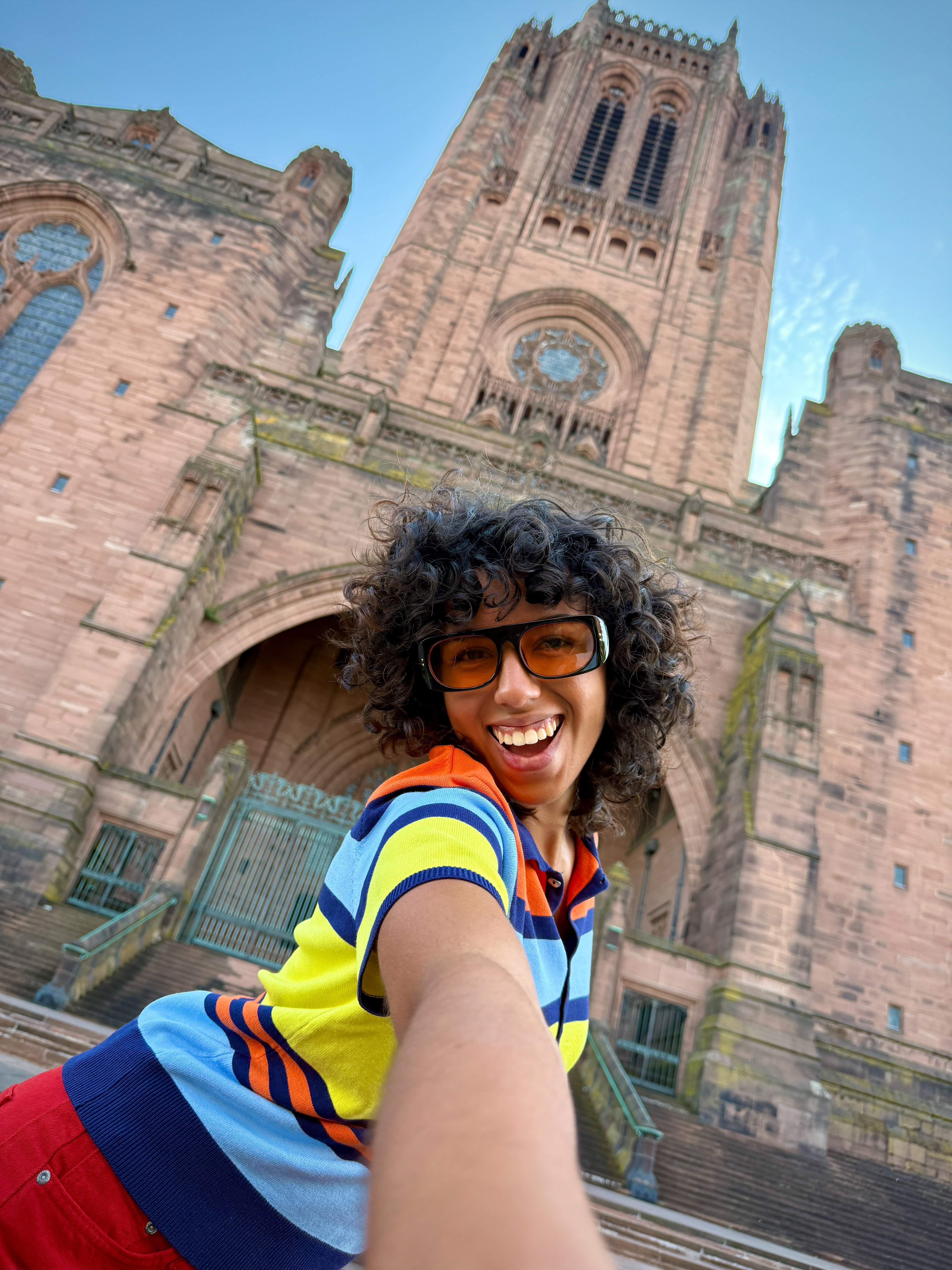 Smiling woman in orange sunglasses taking a selfie at Liverpool Cathedral.