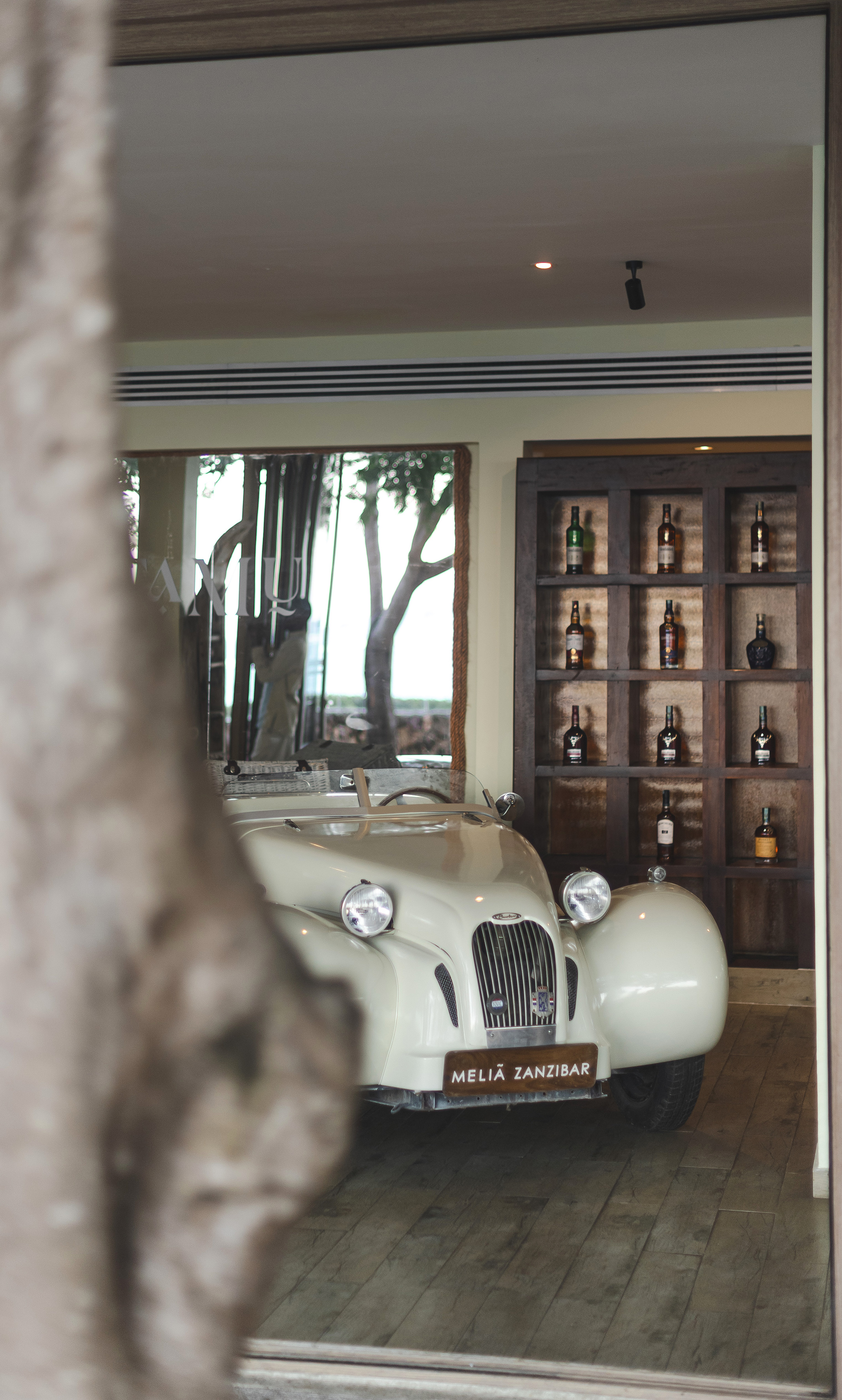 Cream classic car with Melia Zanzibar sign, luxury hotel bar display.