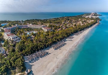 a beach with umbrellas and buildings and trees