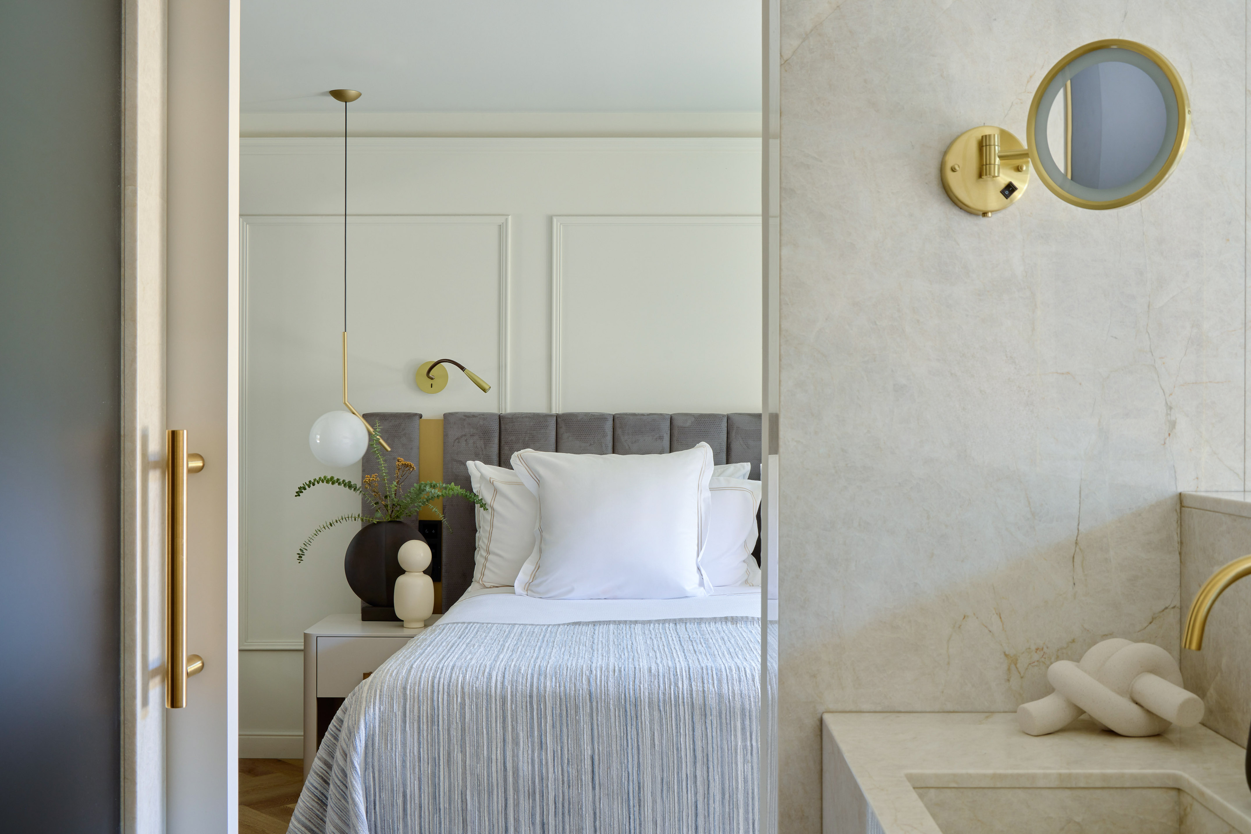 Contemporary bedroom design with gray bed, gold lights, and marble bathroom vanity. - MiM Andorra Meliá Collection, Andorra la Vella
