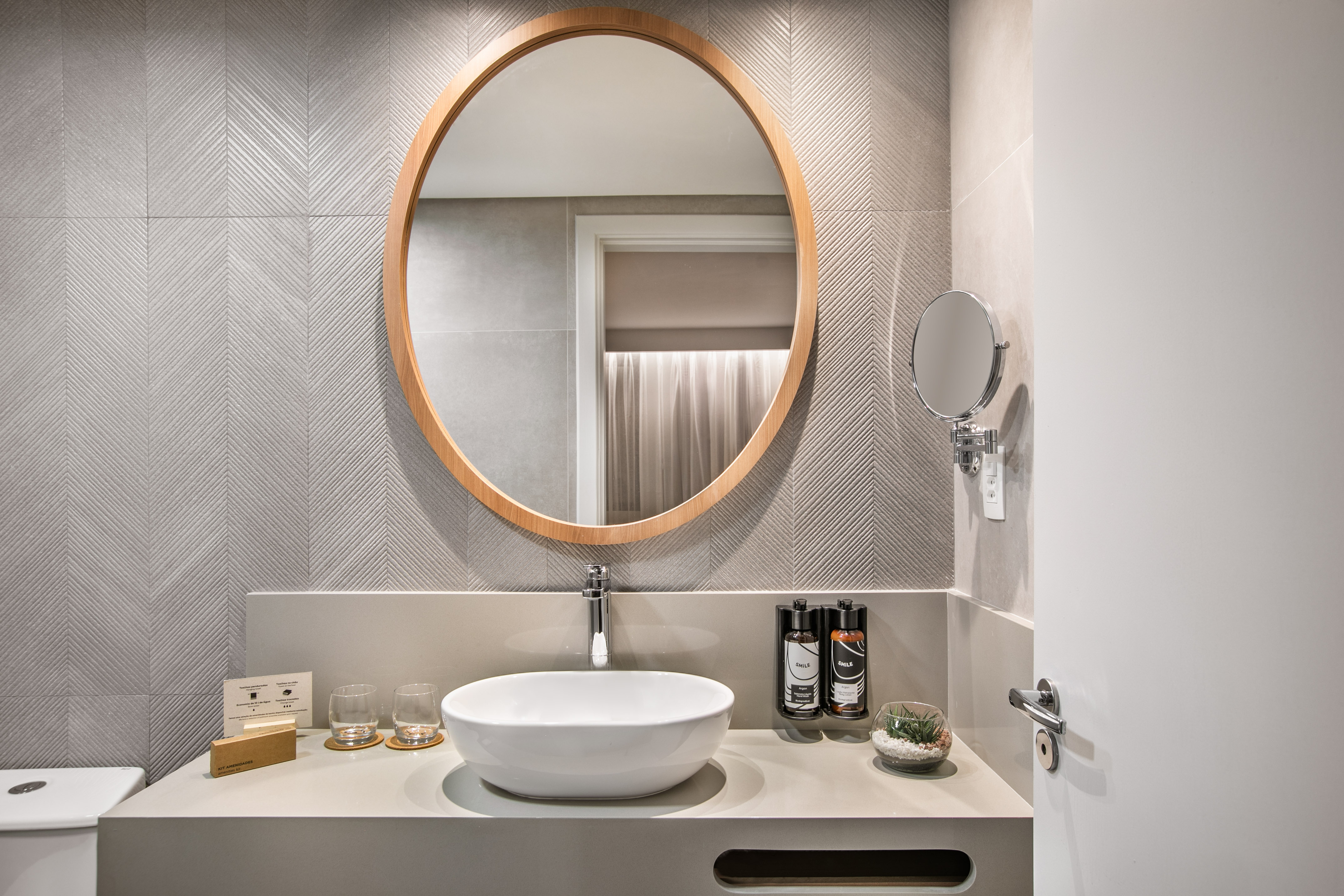 Modern bathroom vanity with round mirror, vessel sink, and gray chevron wall tiles. - The Loft for Families - INNSiDE São Paulo Higienópolis, Sao Paulo
