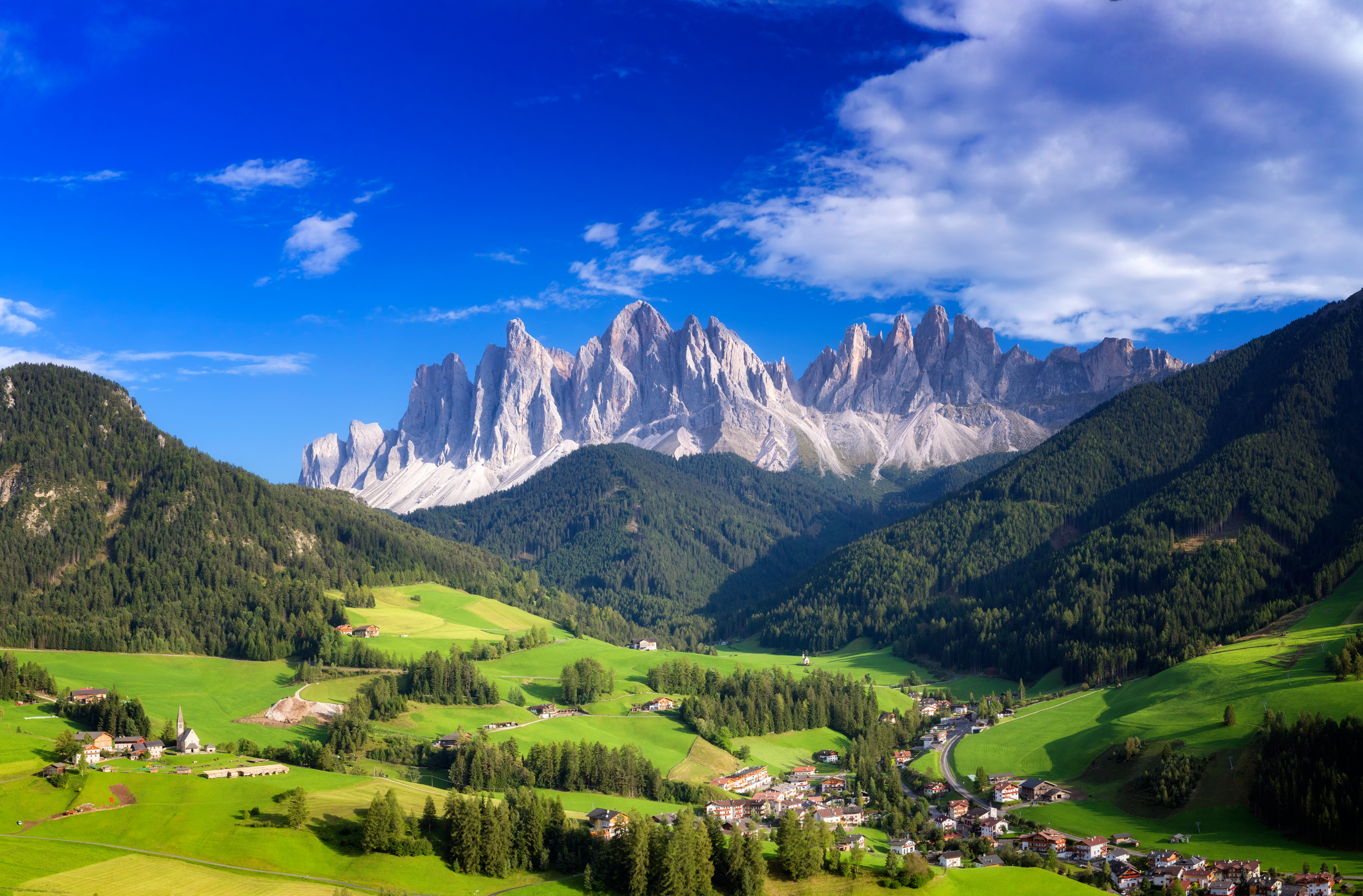a landscape of green hills and mountains with Dolomites in the background