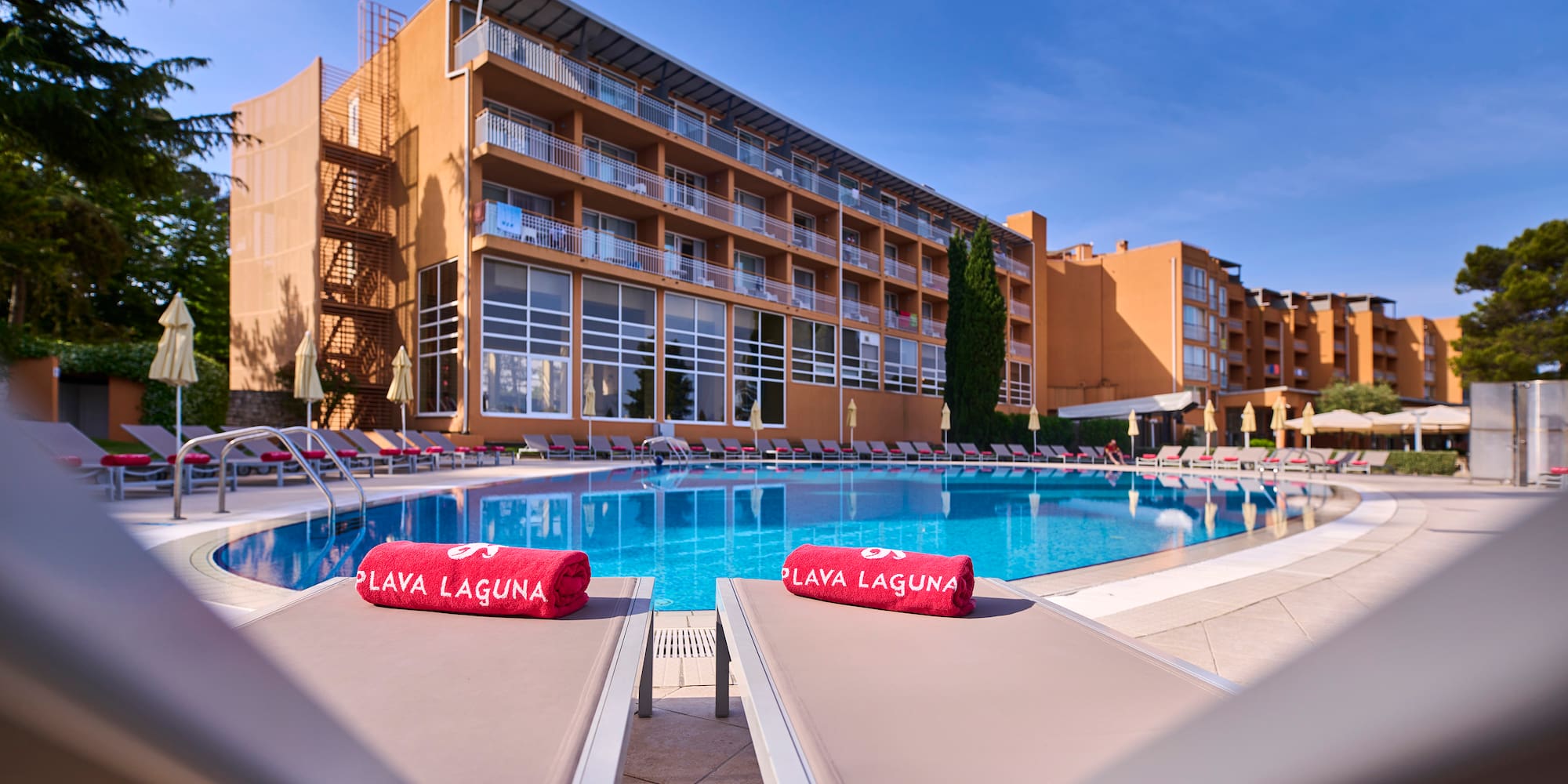 a pool with lounge chairs and red towels