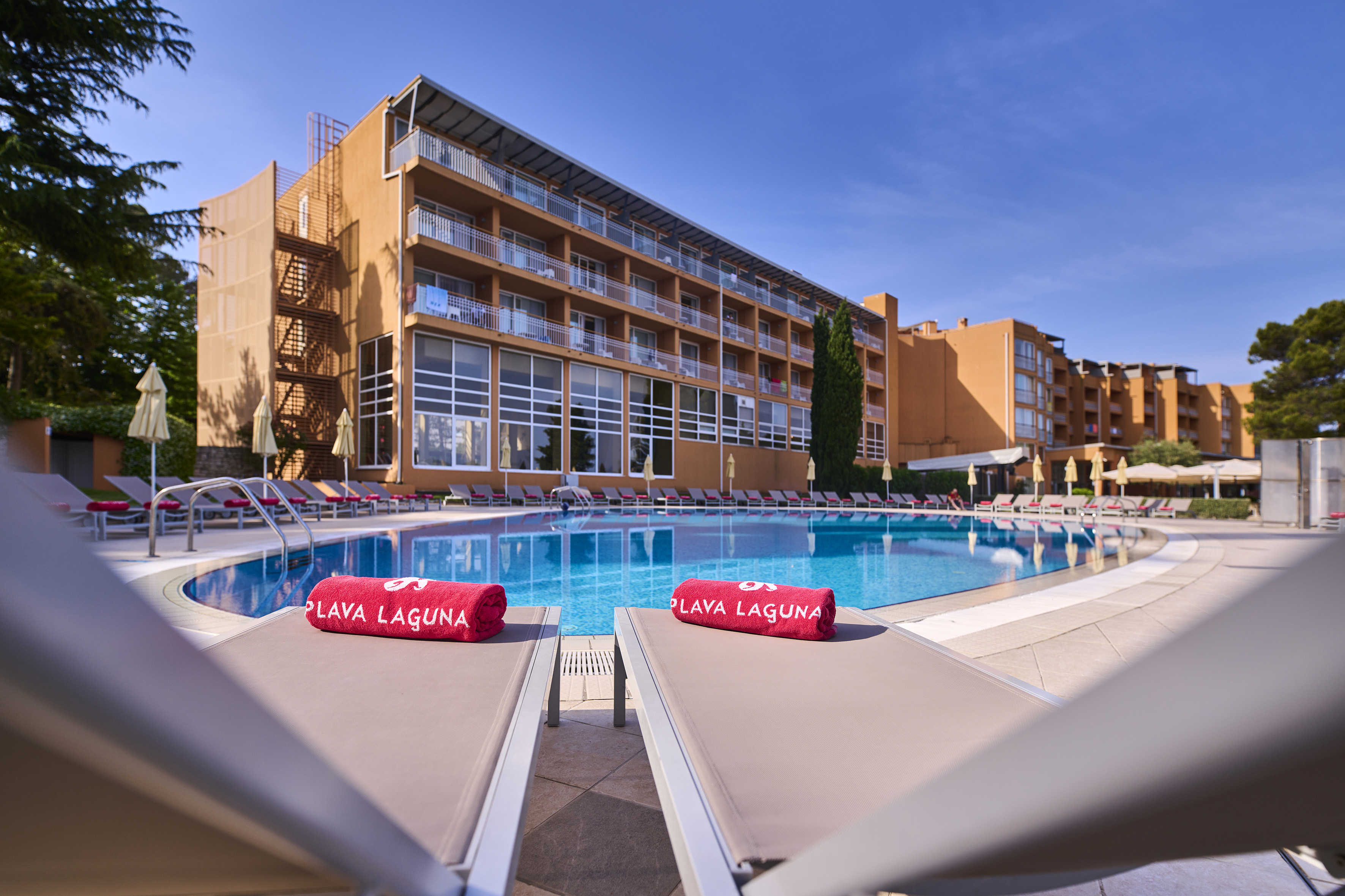 a pool with lounge chairs and red towels