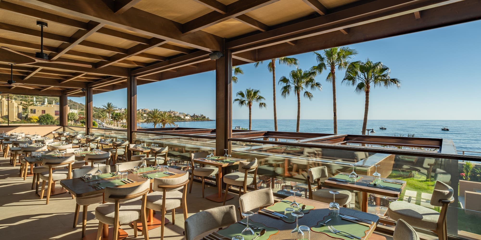 Luxury beachfront restaurant with ocean view and palm trees.