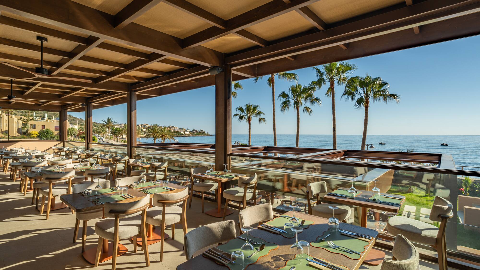 Luxury beachfront restaurant with ocean view and palm trees.
